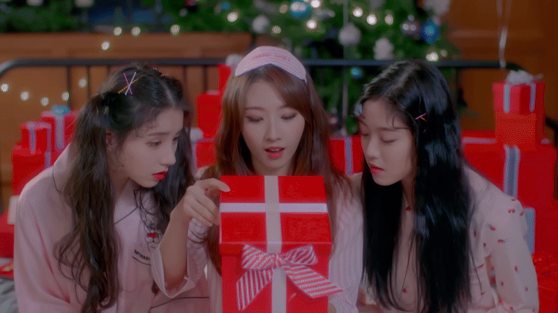 A gif of Heejin, Haseul, and Hyunjin opening a present. As soon as they open it, the top flies off and feathers burst out.